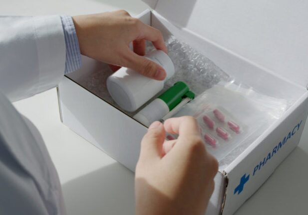 Close-up hand asia woman chemist help pack covid free first aid self recover care on desk give for customer people buy online clinic retail Rx drug store in telehealth telemedicine e-commerce order.